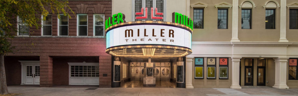 The illuminated marquee of the Miller Theater, displaying the theater's name in bold letters, set against the historic building facade.